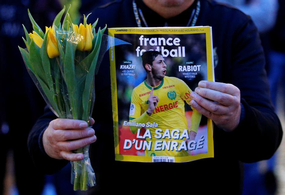 A man holds a sports magazine and yellow tulips as fans gather in the Nantes city center after news that newly-signed Cardiff City soccer player Emiliano Sala was missing after the light aircraft he was travelling in disappeared between France and England | Autor: STEPHANE MAHE